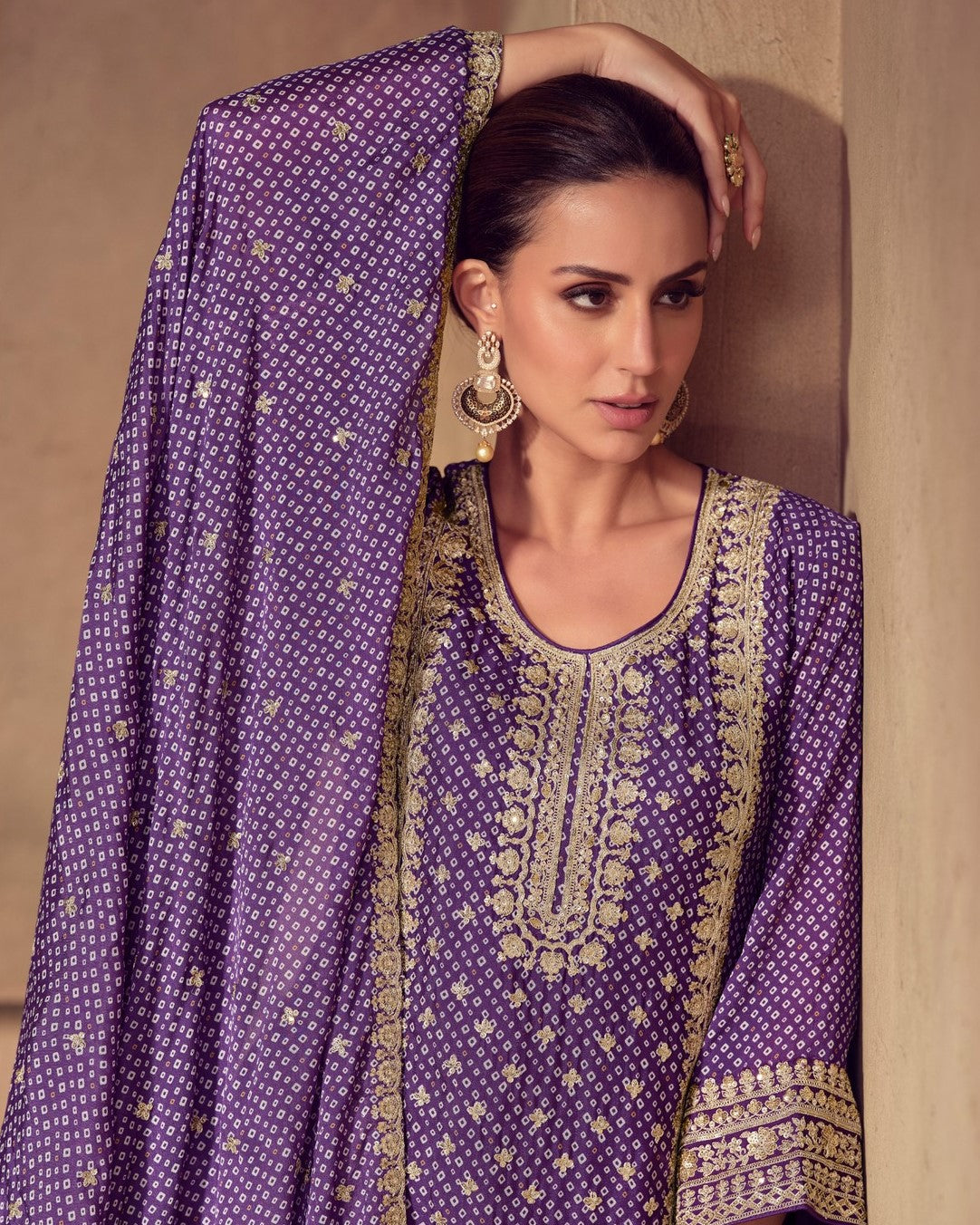 Woman wearing a purple embroidered traditional outfit with gold detailing.