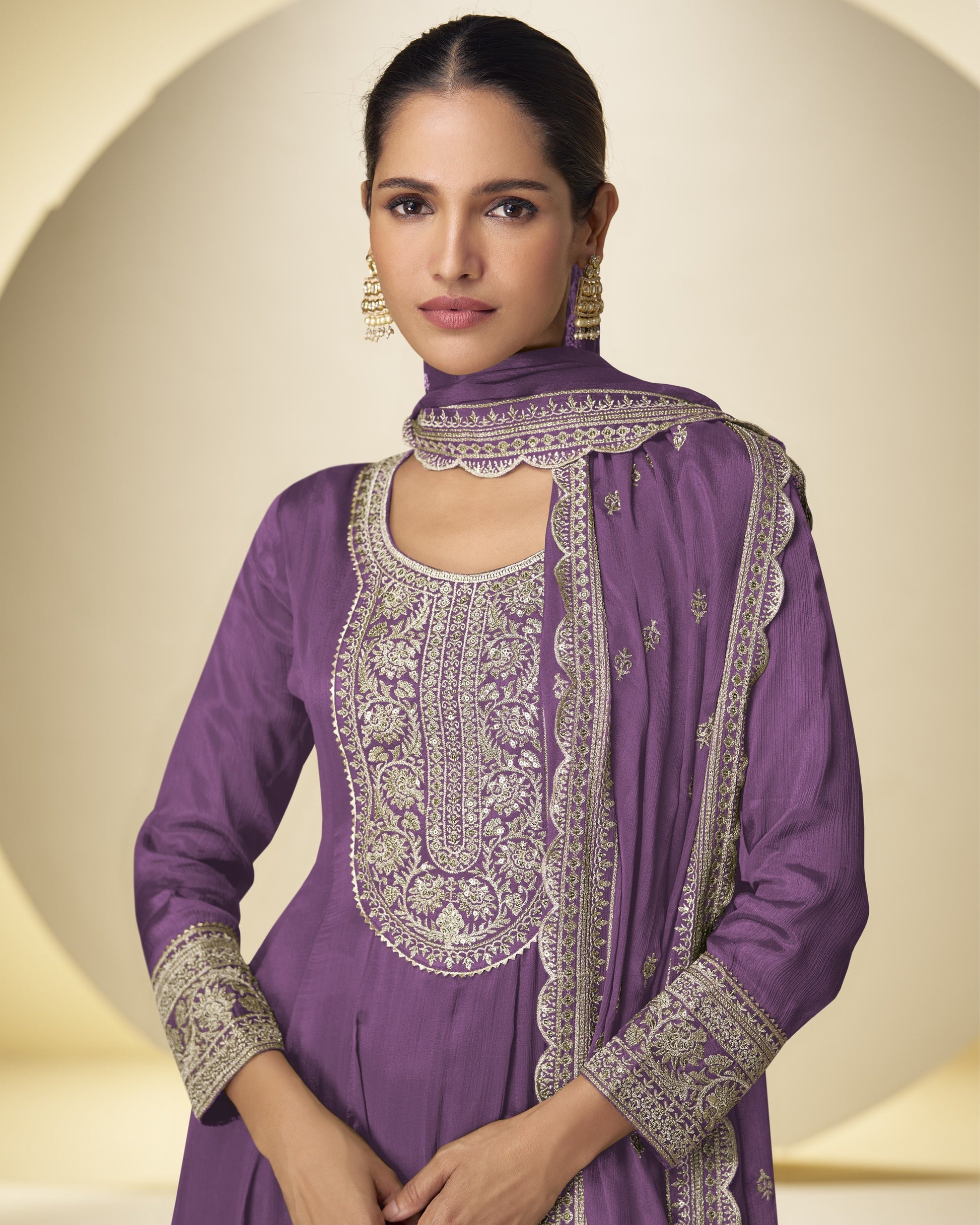 Woman wearing a purple embroidered outfit with a matching dupatta on a beige background