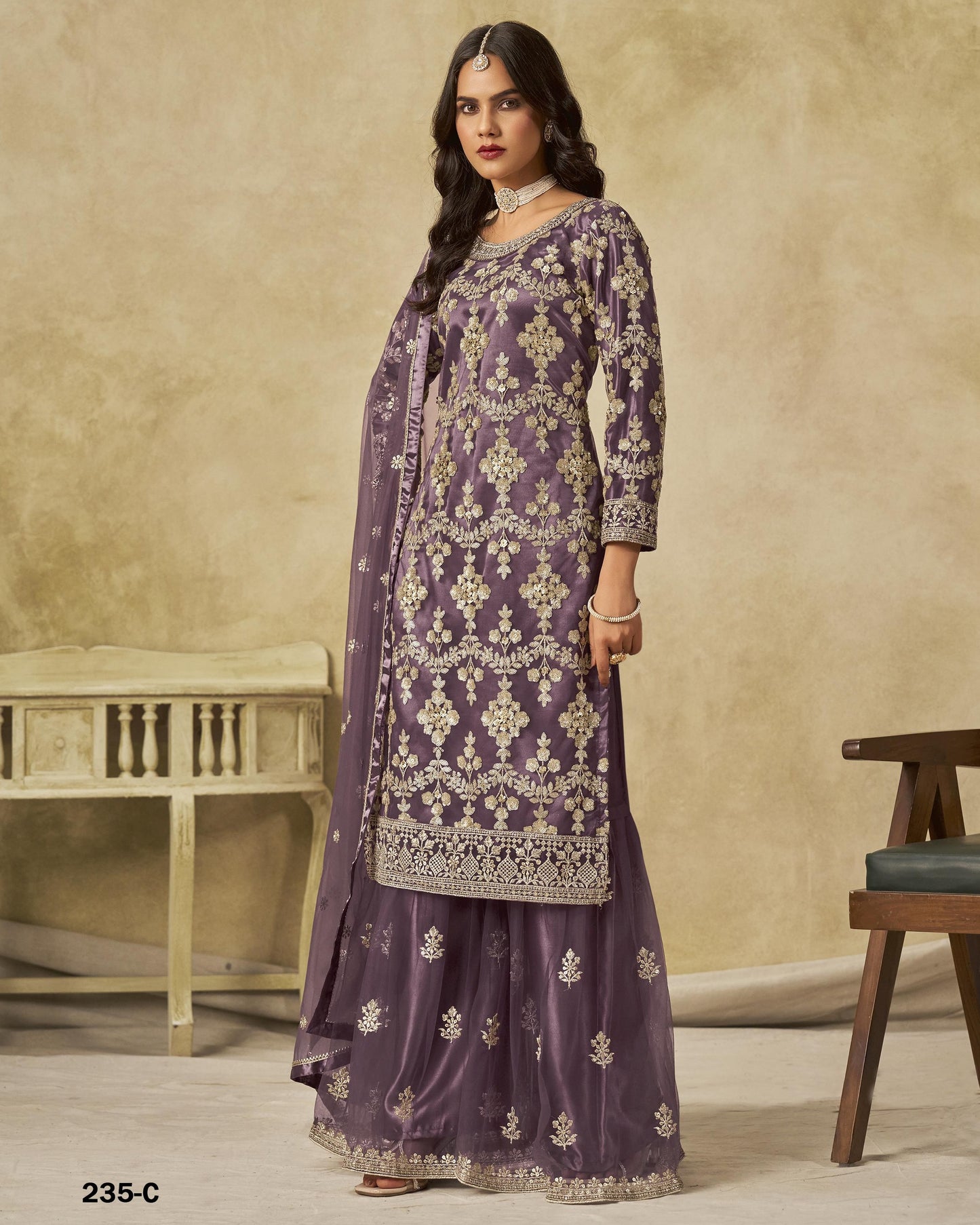 Woman wearing a purple embroidered traditional outfit with a beige background