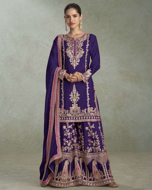 Woman wearing a purple embroidered traditional outfit with a plain background