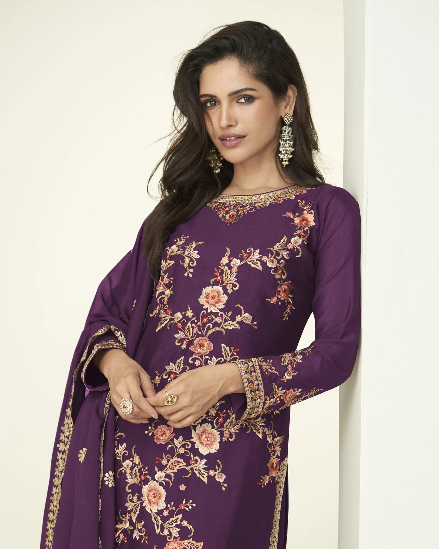 Woman wearing a purple embroidered dress against a white background