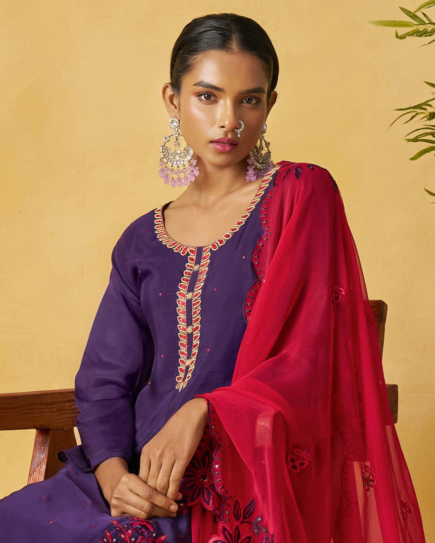 Woman wearing a purple embroidered top with a red dupatta against a yellow background