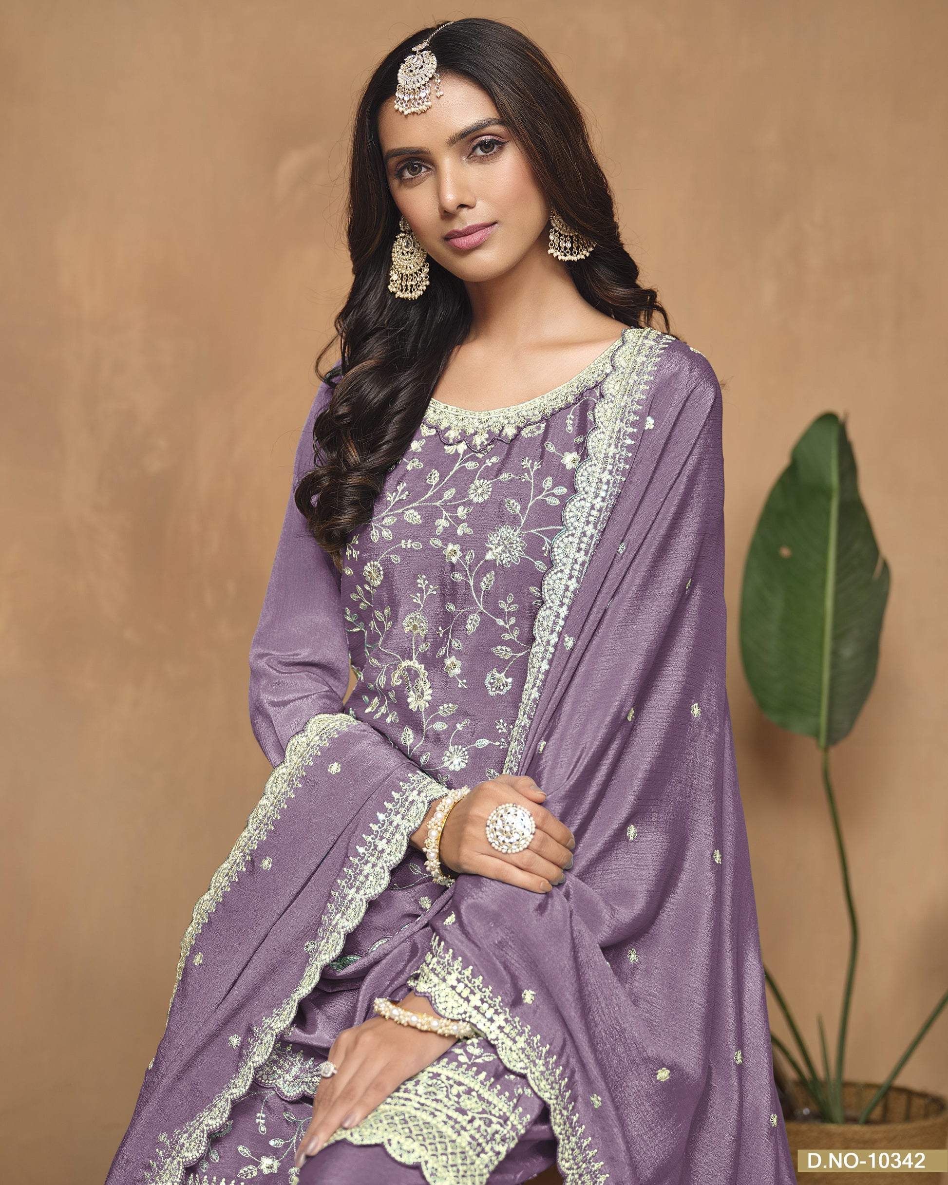 Woman wearing a purple traditional outfit with green accents against a beige background