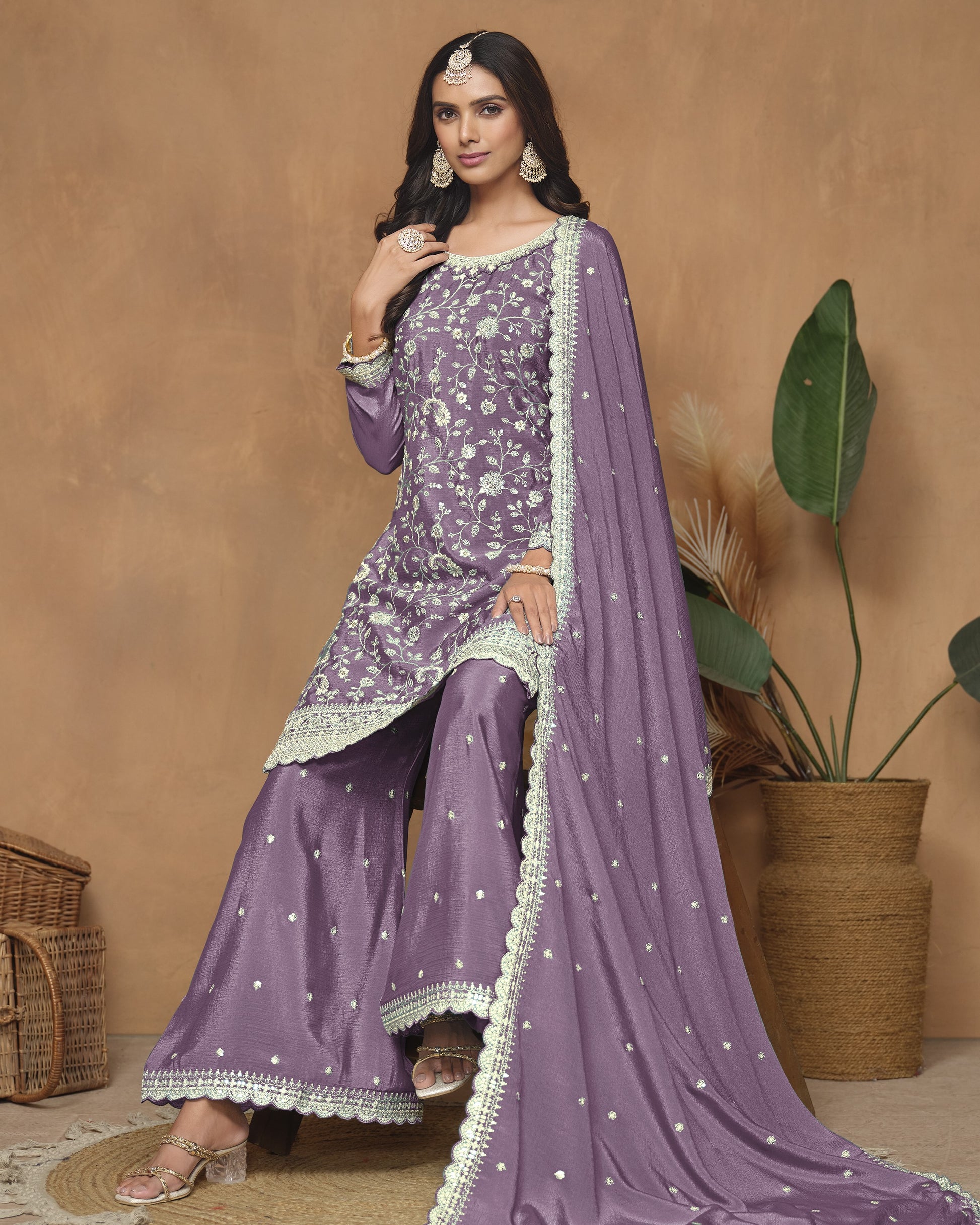 Woman in a purple traditional outfit with white patterns against a beige background