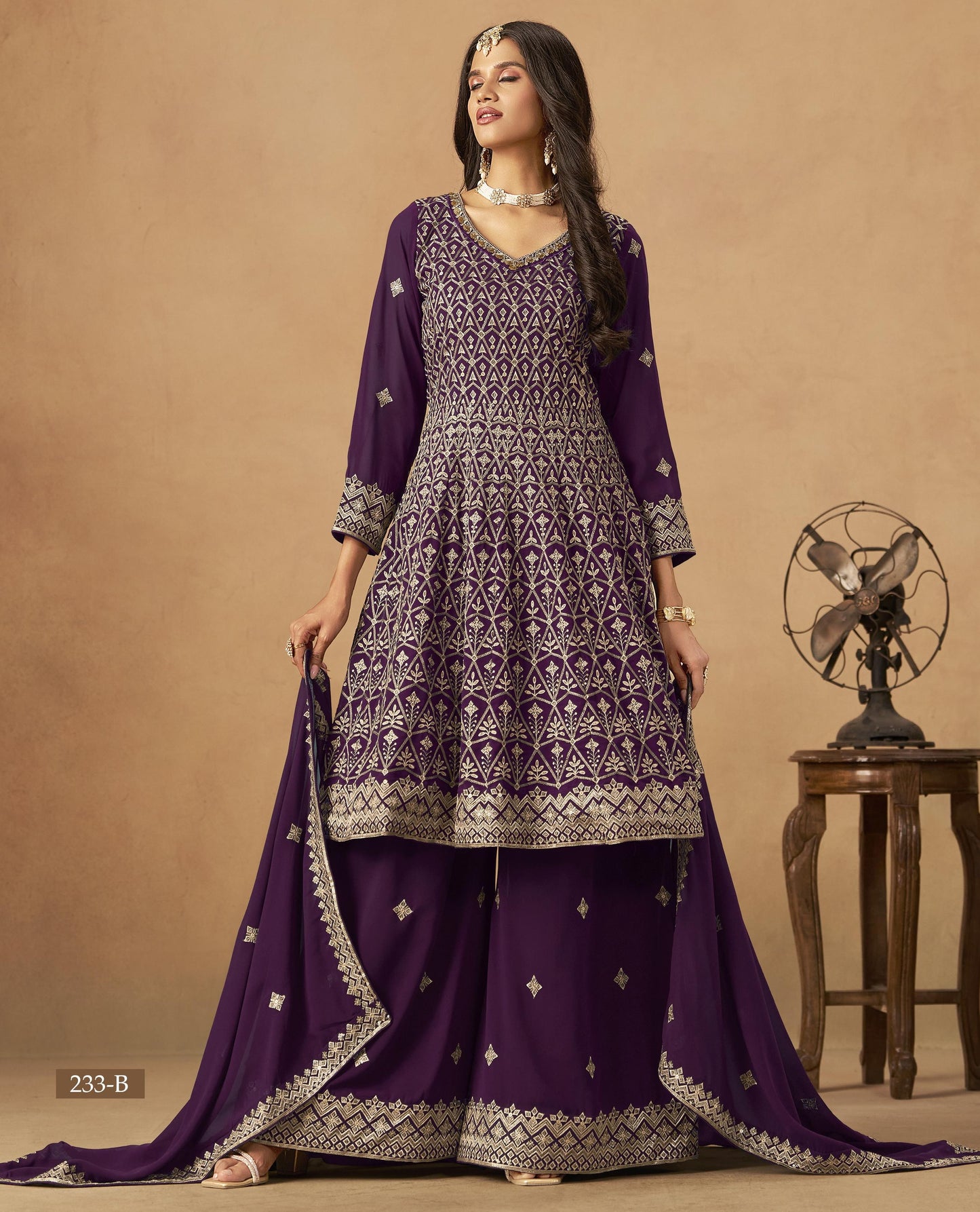 Woman wearing a purple and gold traditional outfit with jewelry on a beige background
