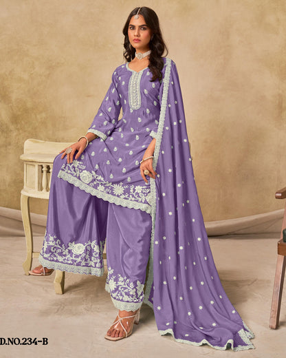 Woman wearing a purple traditional outfit with white embroidery in a room setting.