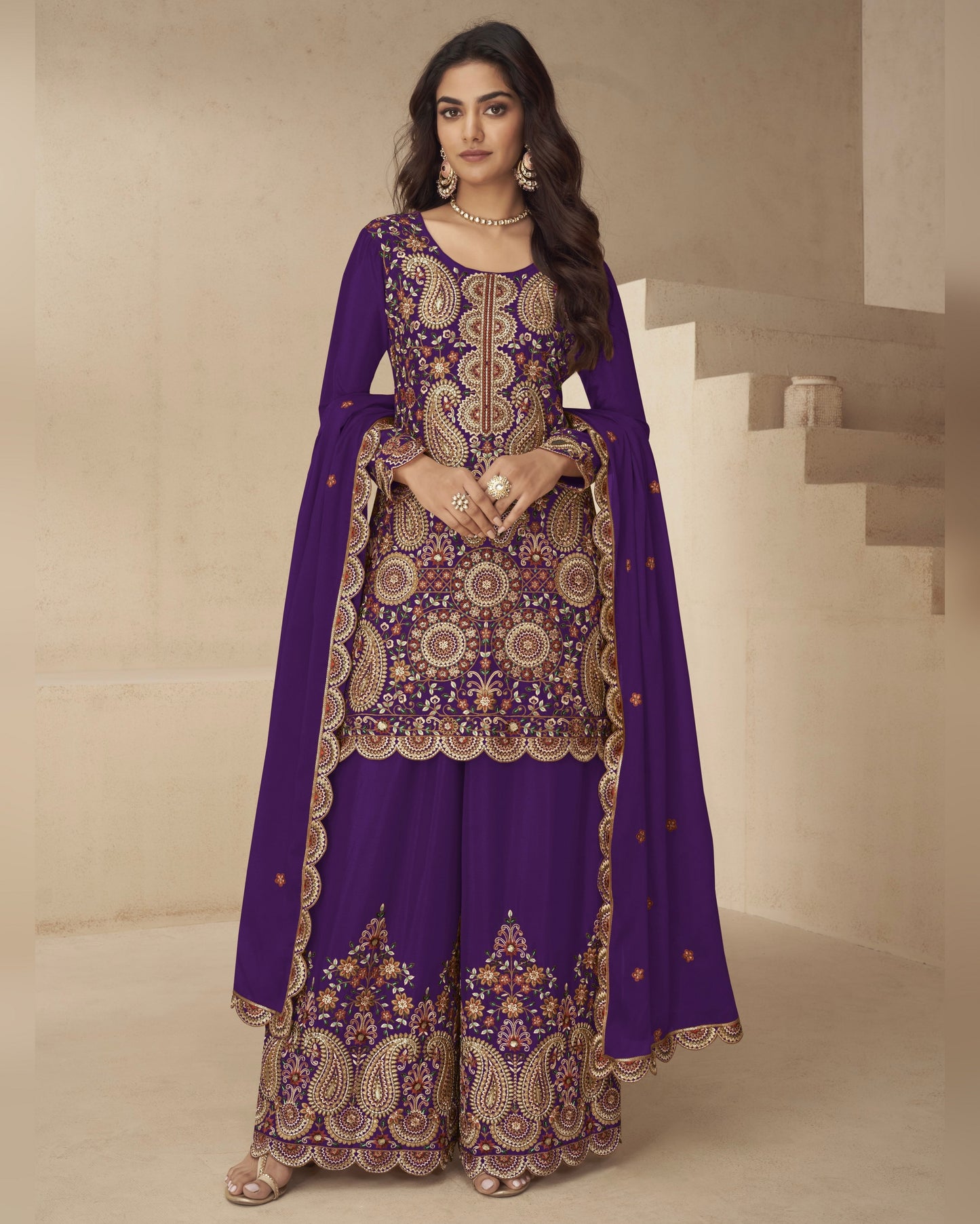 Woman wearing a purple embroidered traditional outfit in a neutral setting