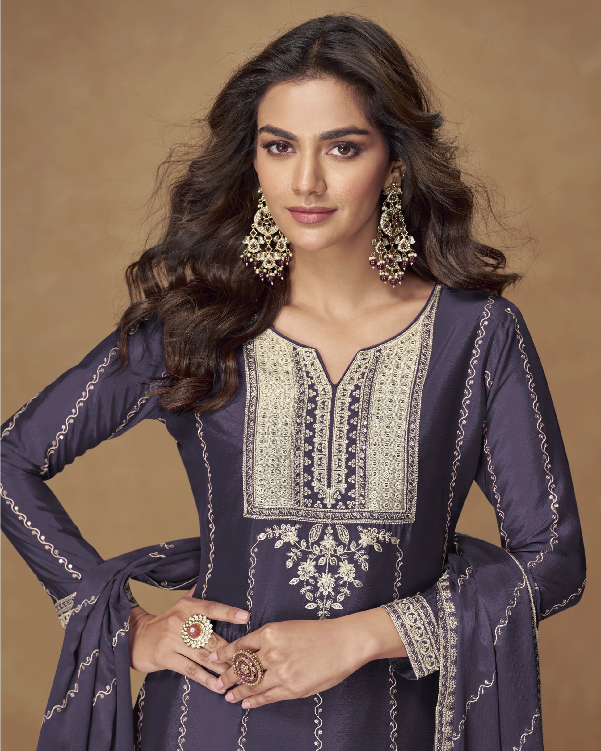 Woman wearing an embroidered traditional outfit with jewelry on a beige background