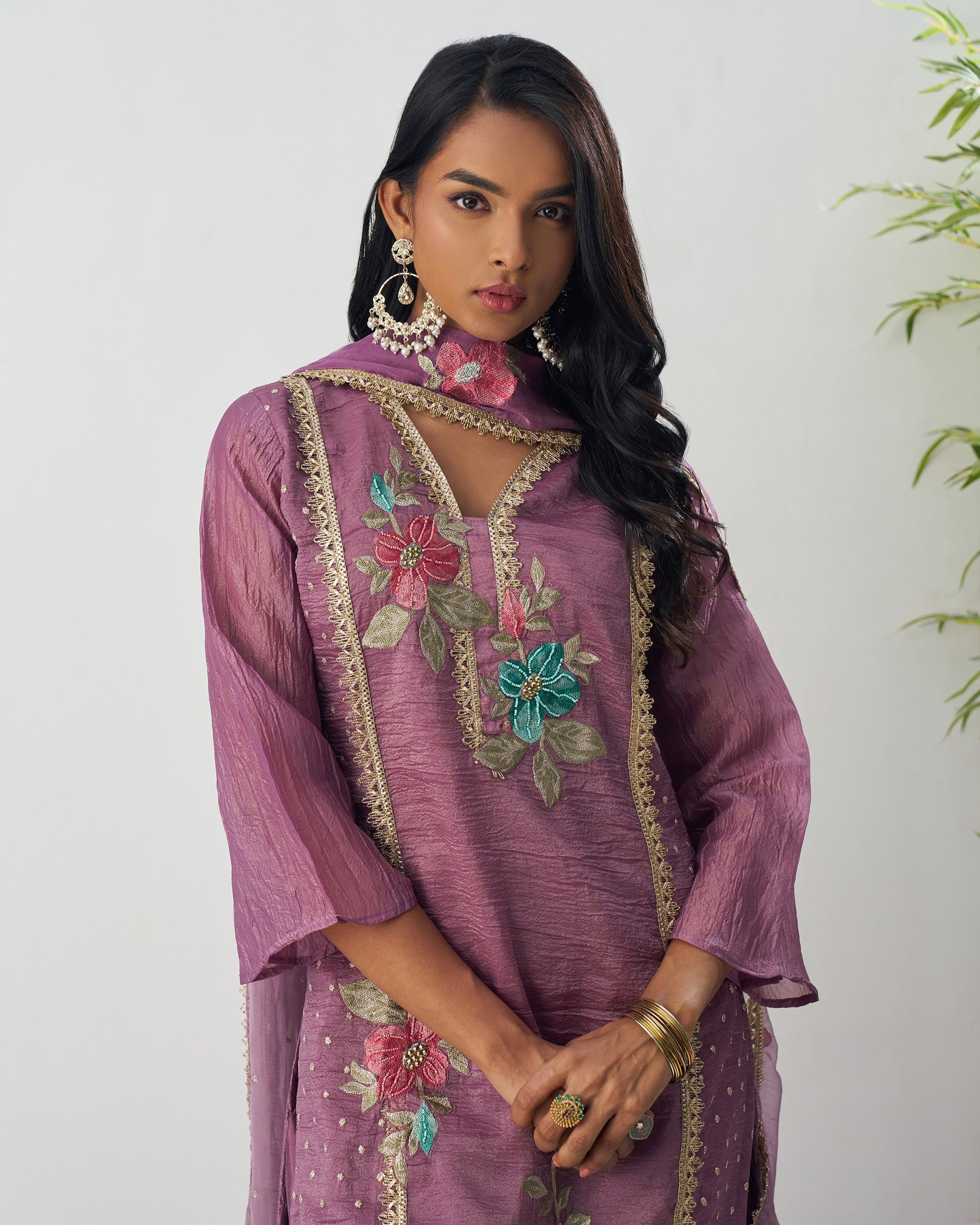 Woman wearing a purple embroidered dress with floral patterns on a white background