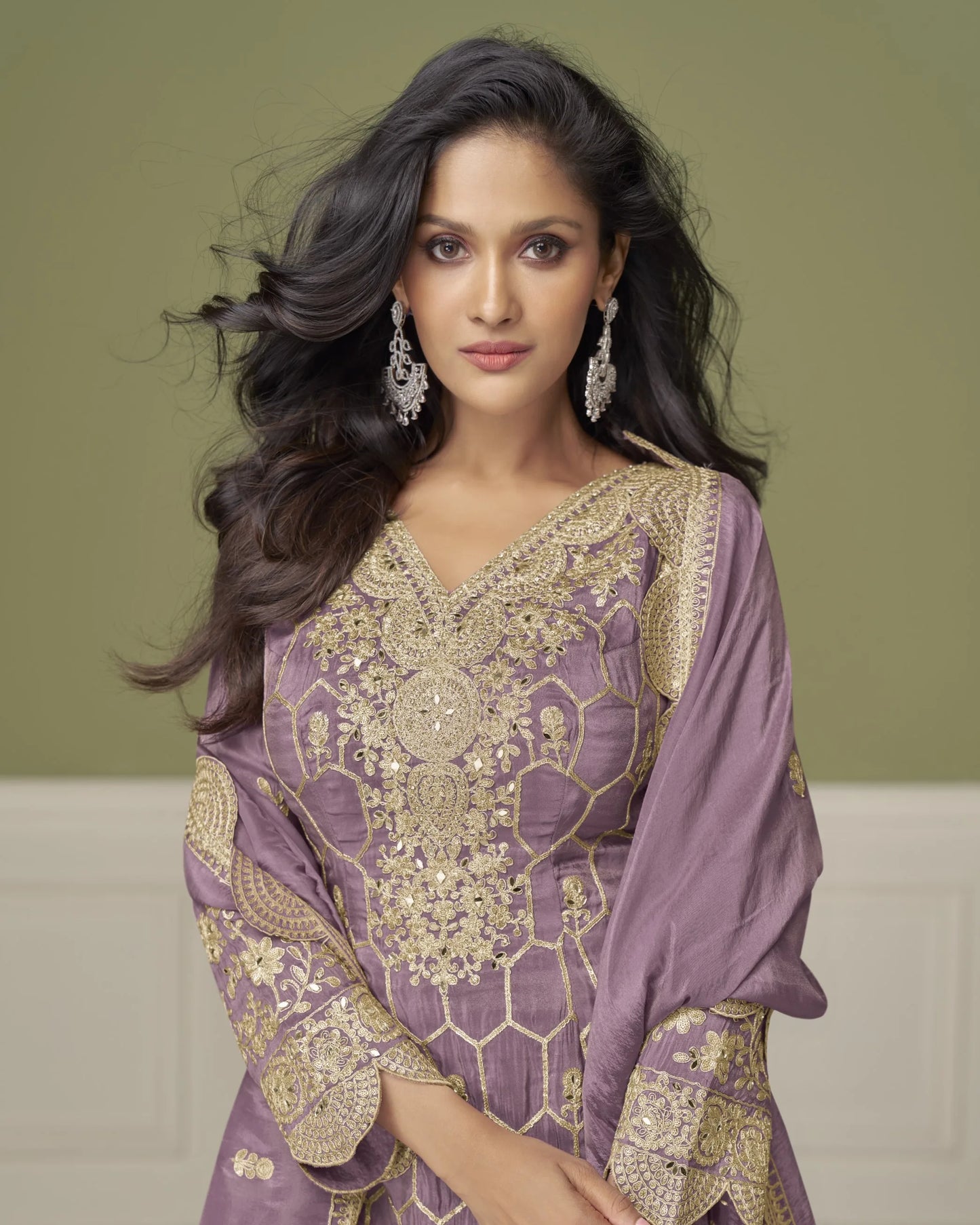 Woman wearing a purple embroidered outfit with gold details against a green background