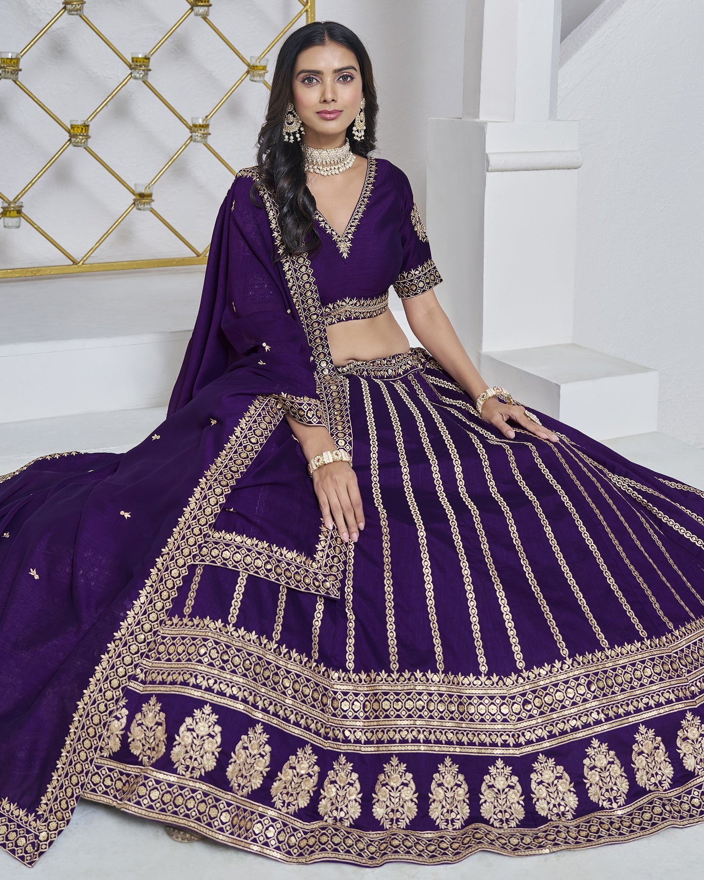 Woman wearing a purple embroidered traditional outfit in a white room.