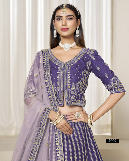 Woman wearing a purple and gray traditional outfit with intricate designs against a white curtain background.