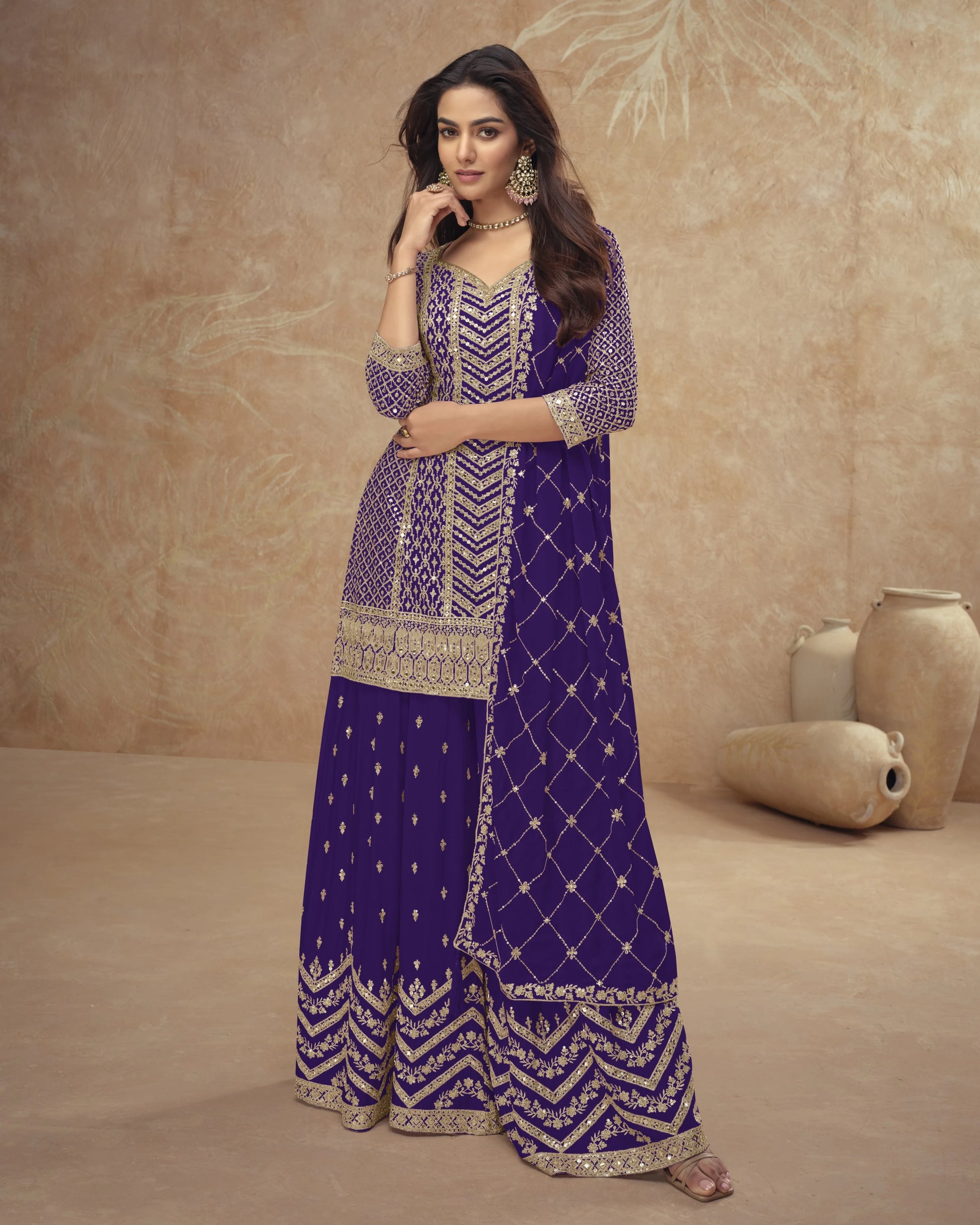 Woman wearing a purple and gold embroidered traditional outfit against a beige background