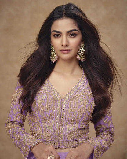 Woman wearing a purple and gold embroidered traditional outfit with a beige background