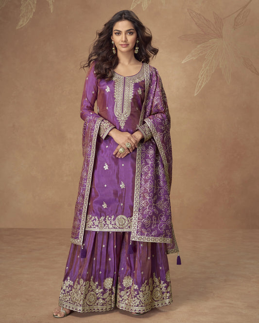 Woman wearing a traditional purple embroidered outfit on a brown background