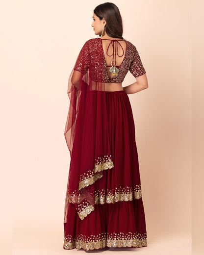 Maroon traditional outfit with gold embroidery on a beige background