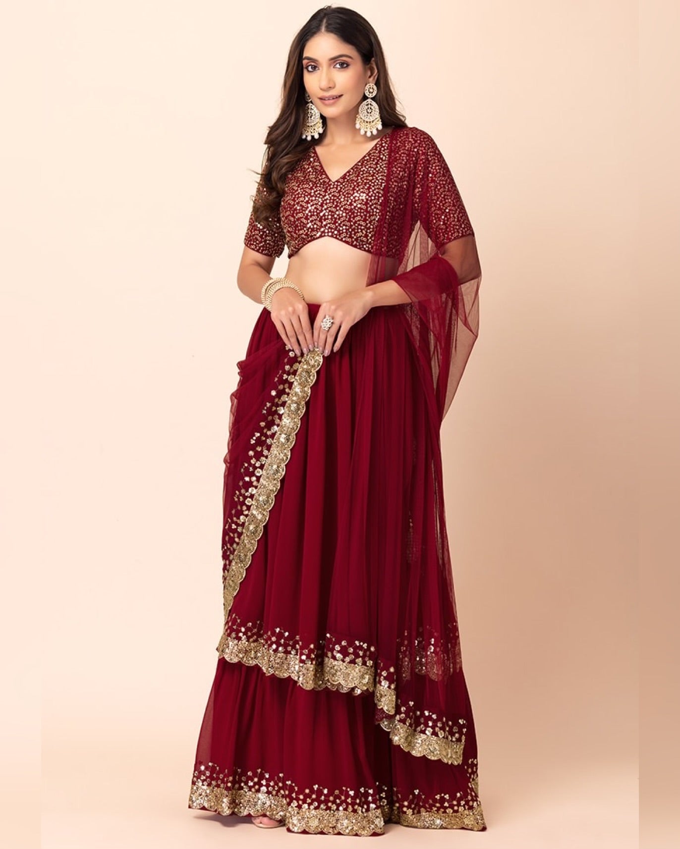 Maroon saree with gold border worn by a model on a beige background