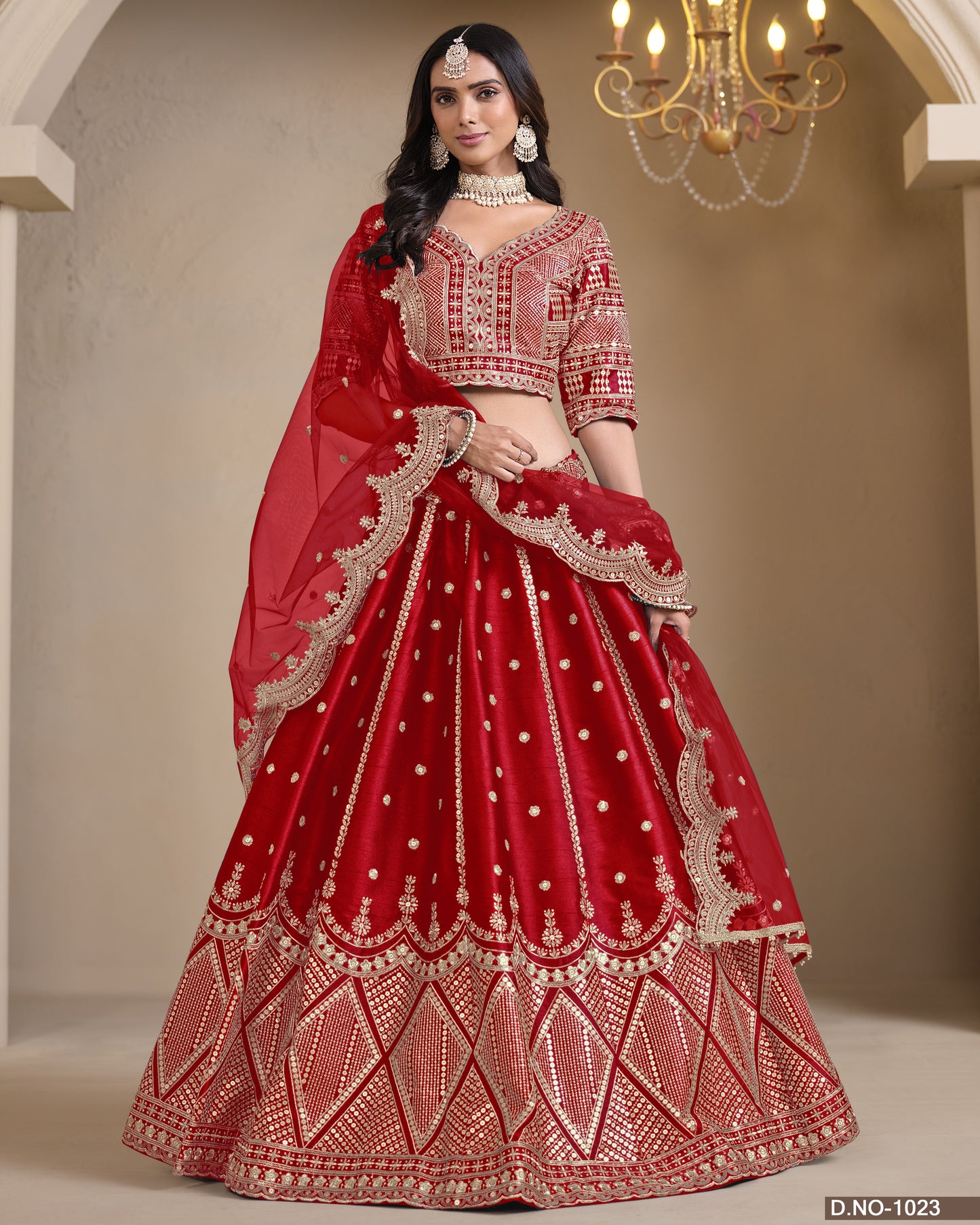 Woman wearing a red embroidered lehenga with gold details in an indoor setting.