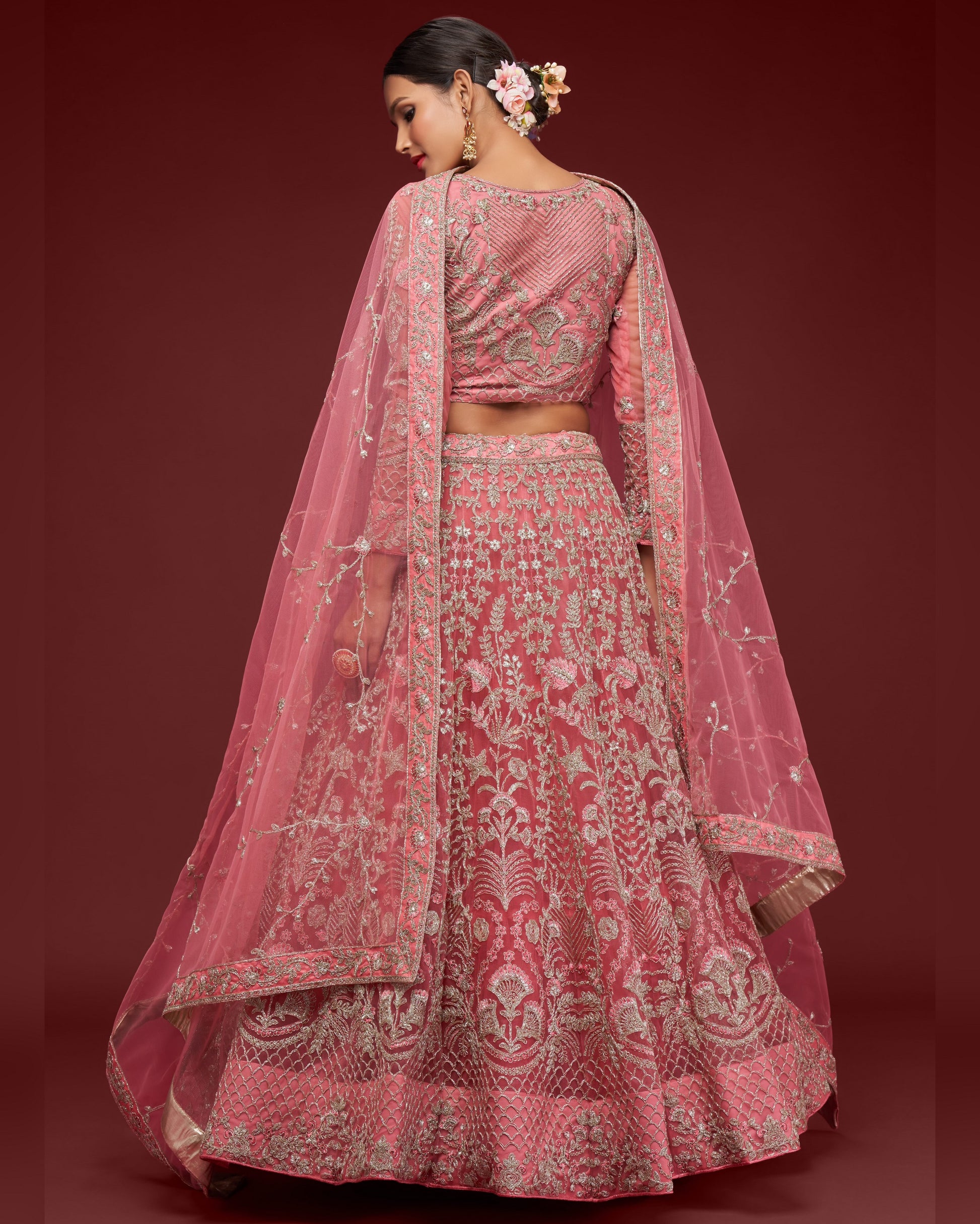 Woman wearing a pink embroidered traditional outfit with a red background