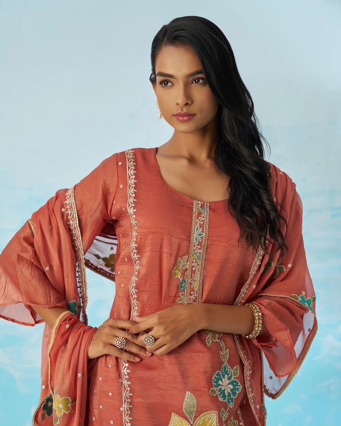 Woman wearing a traditional outfit with floral patterns against a light blue background