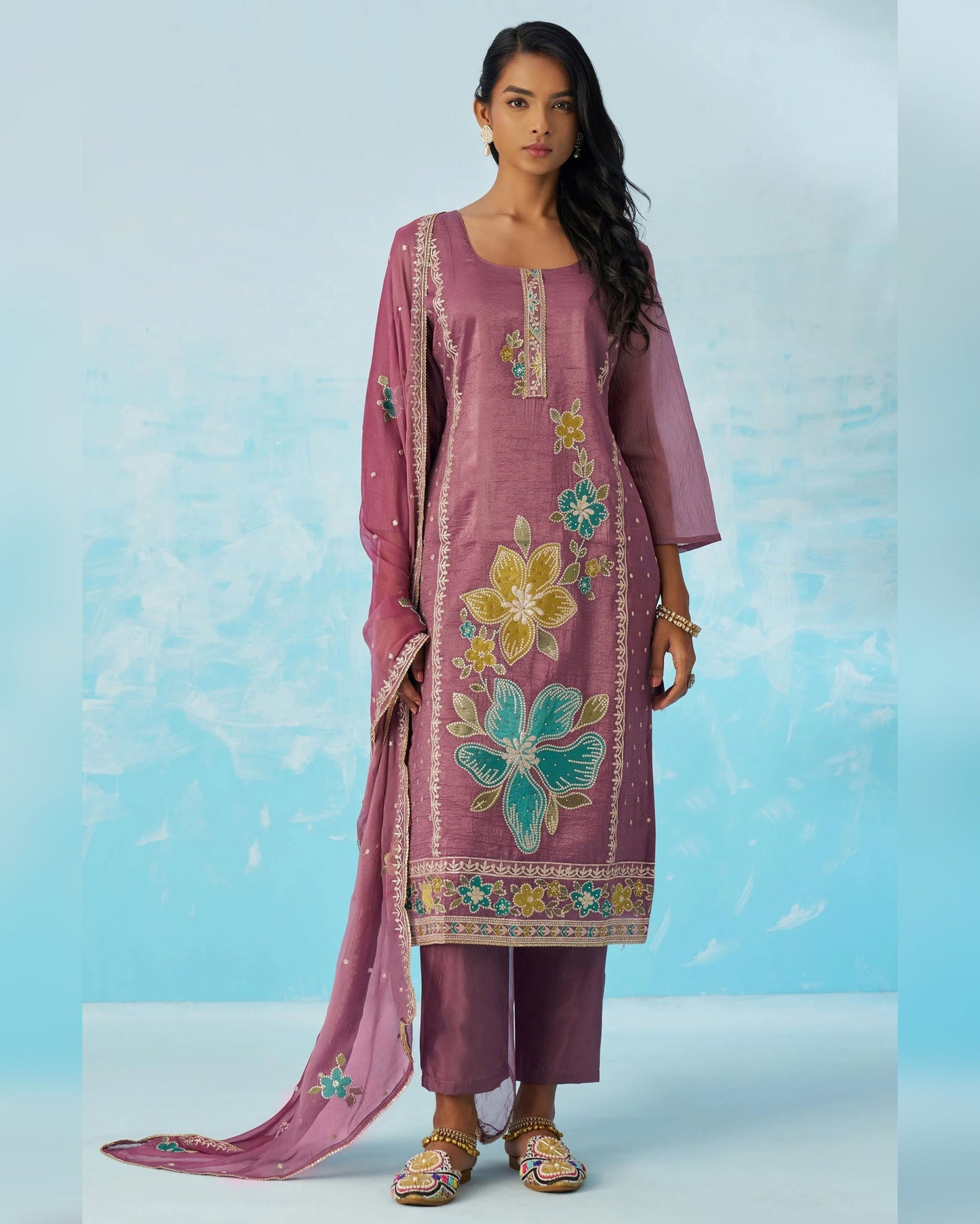 Woman wearing a pink embroidered traditional outfit with a blue background