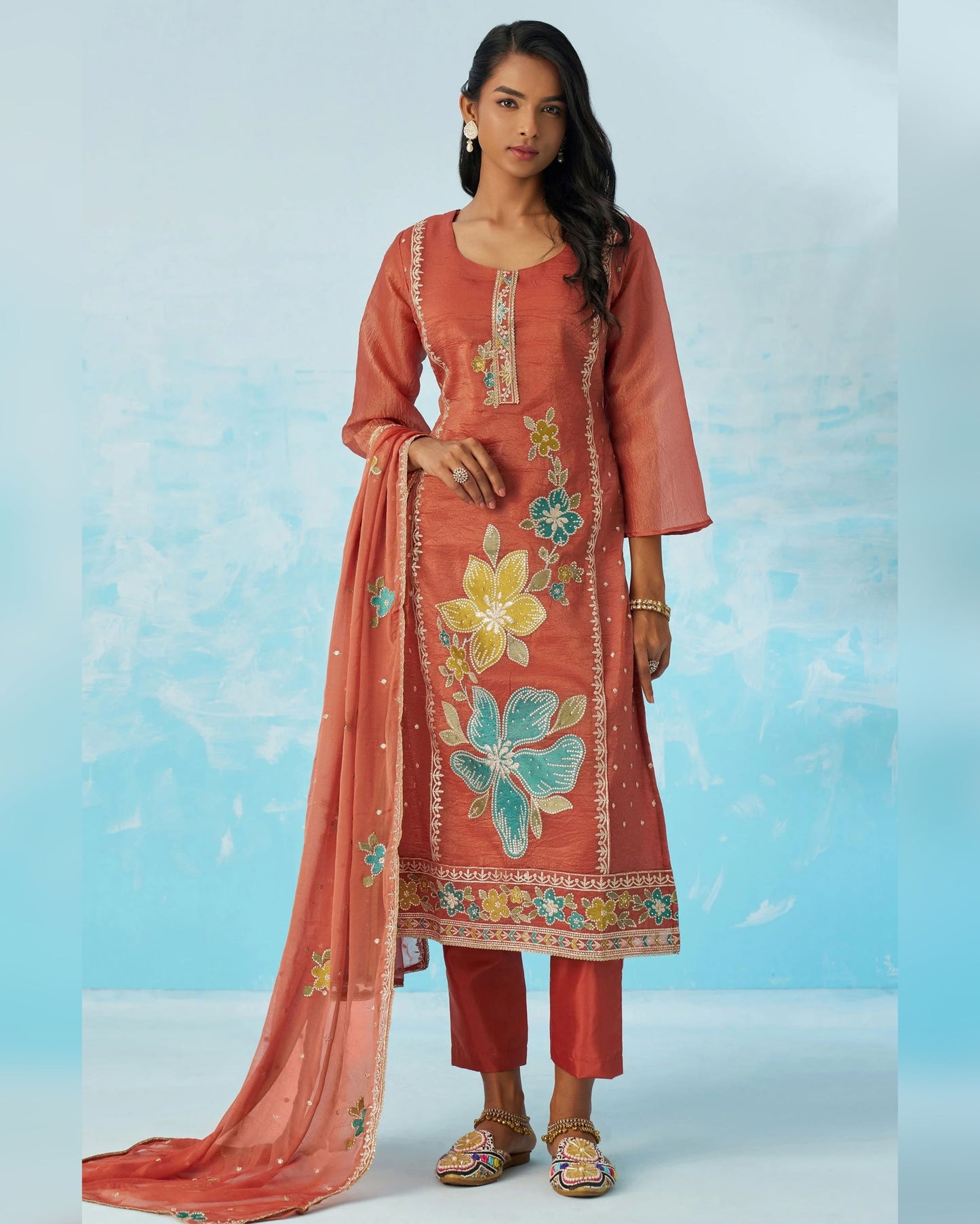 Woman wearing a traditional outfit with floral embroidery on a light blue background