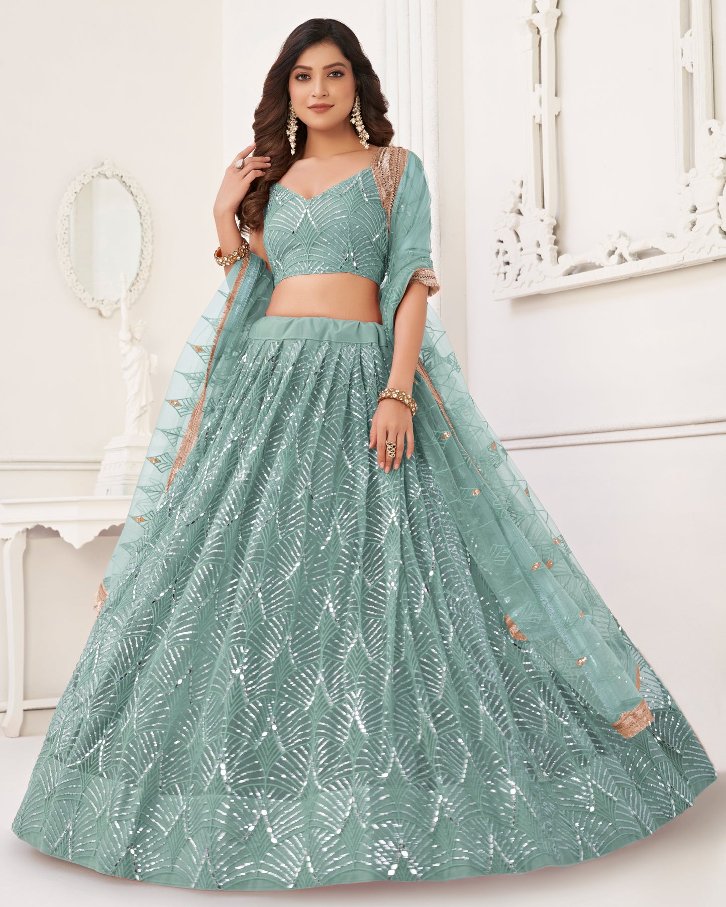 Woman wearing a green traditional outfit with leaf patterns indoors.