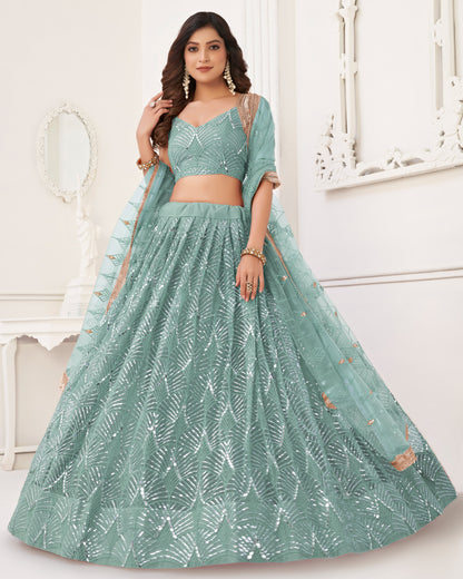 Woman wearing a green traditional outfit with leaf patterns indoors.