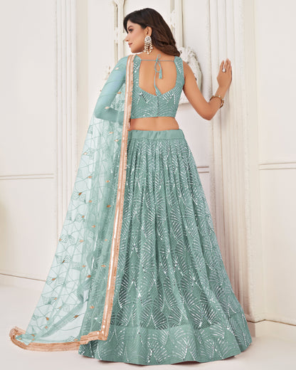 Woman wearing a light blue embroidered lehenga with a matching top against a white background