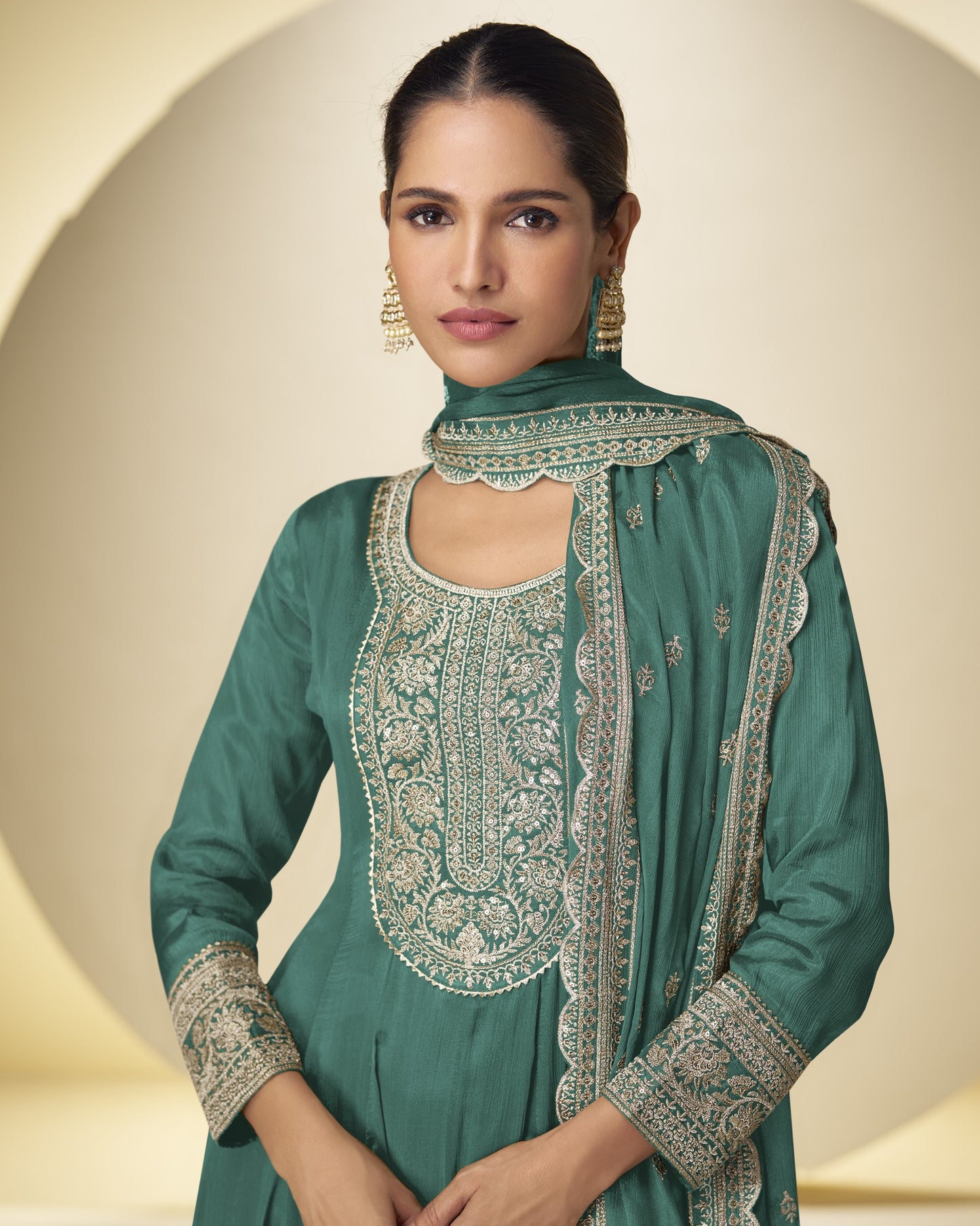 Woman wearing a green embroidered traditional outfit with a plain background