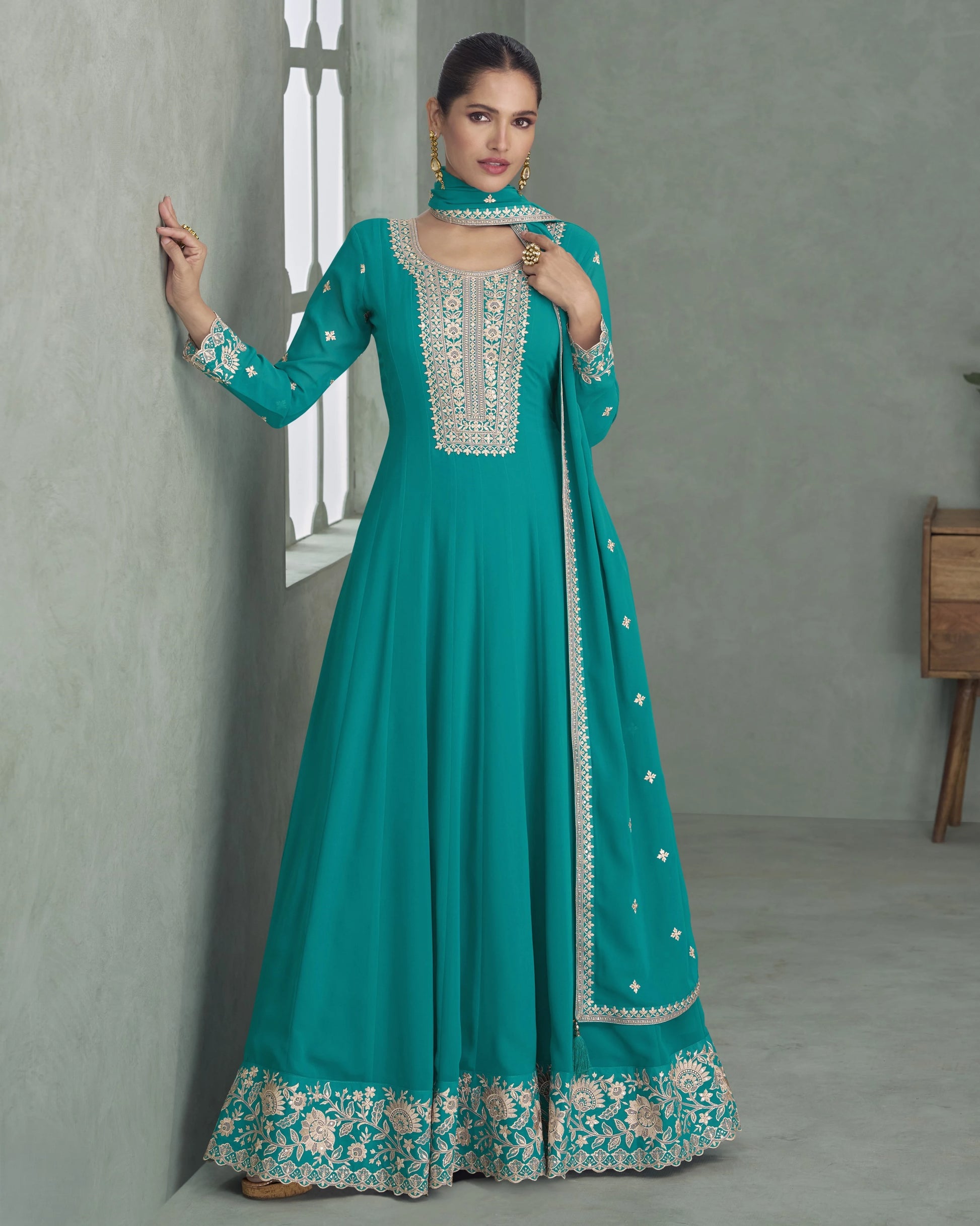 Teal traditional outfit with intricate embroidery on a plain background