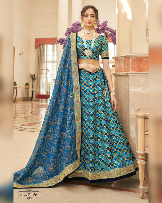Woman in a blue and green traditional outfit with a matching dupatta in an indoor setting.