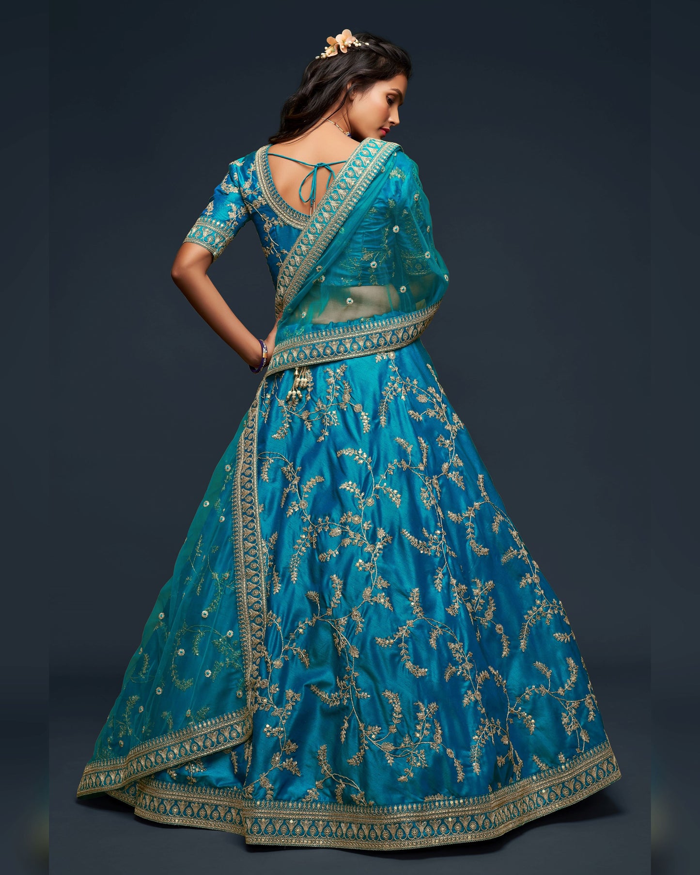 Woman wearing a blue embroidered traditional outfit on a dark background