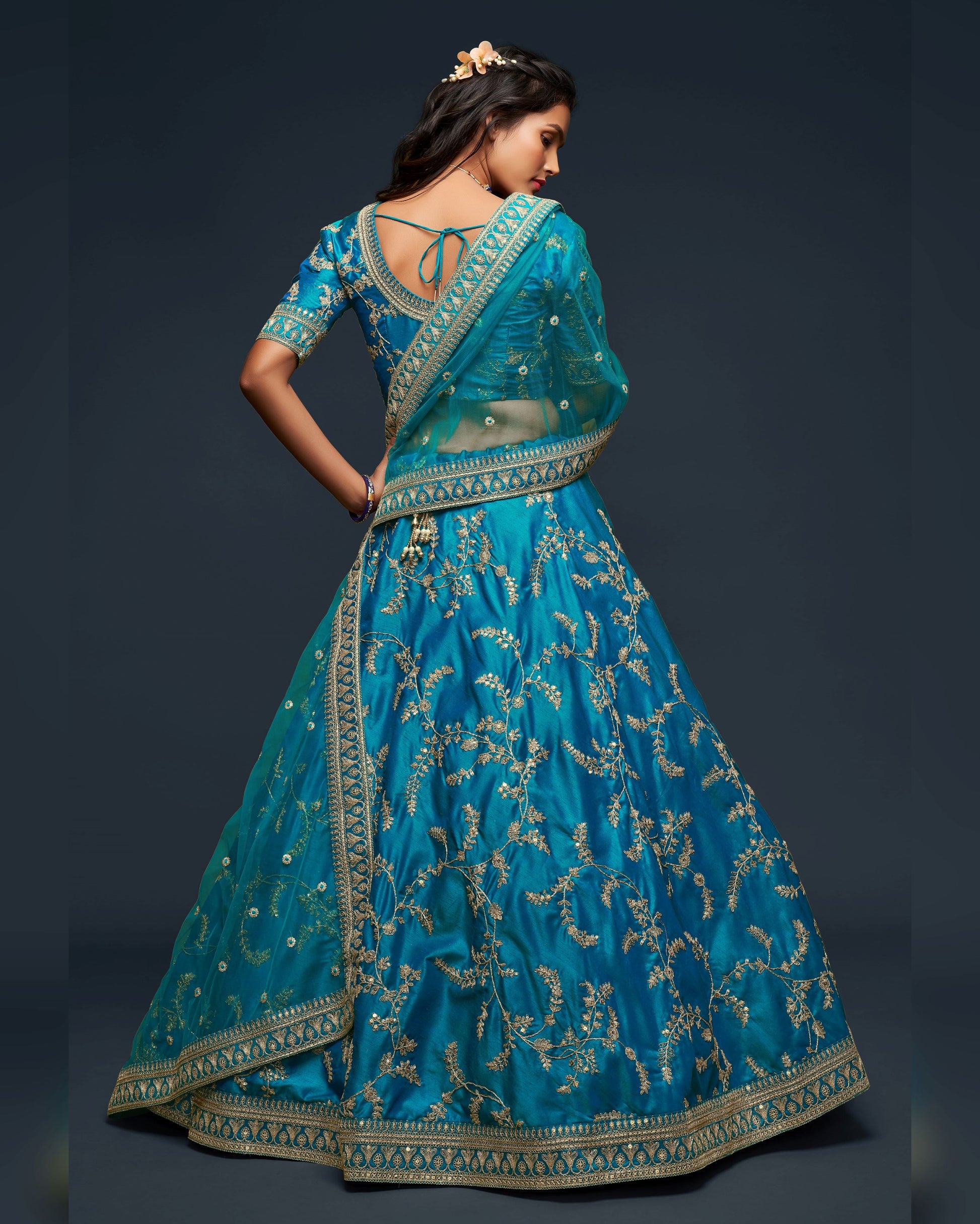 Woman wearing a blue embroidered traditional outfit on a dark background