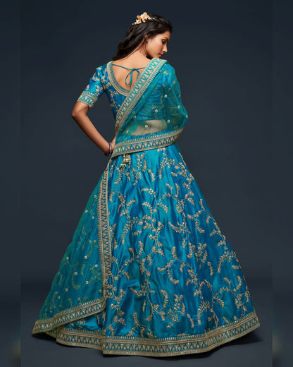 Woman wearing a blue embroidered traditional outfit on a dark background