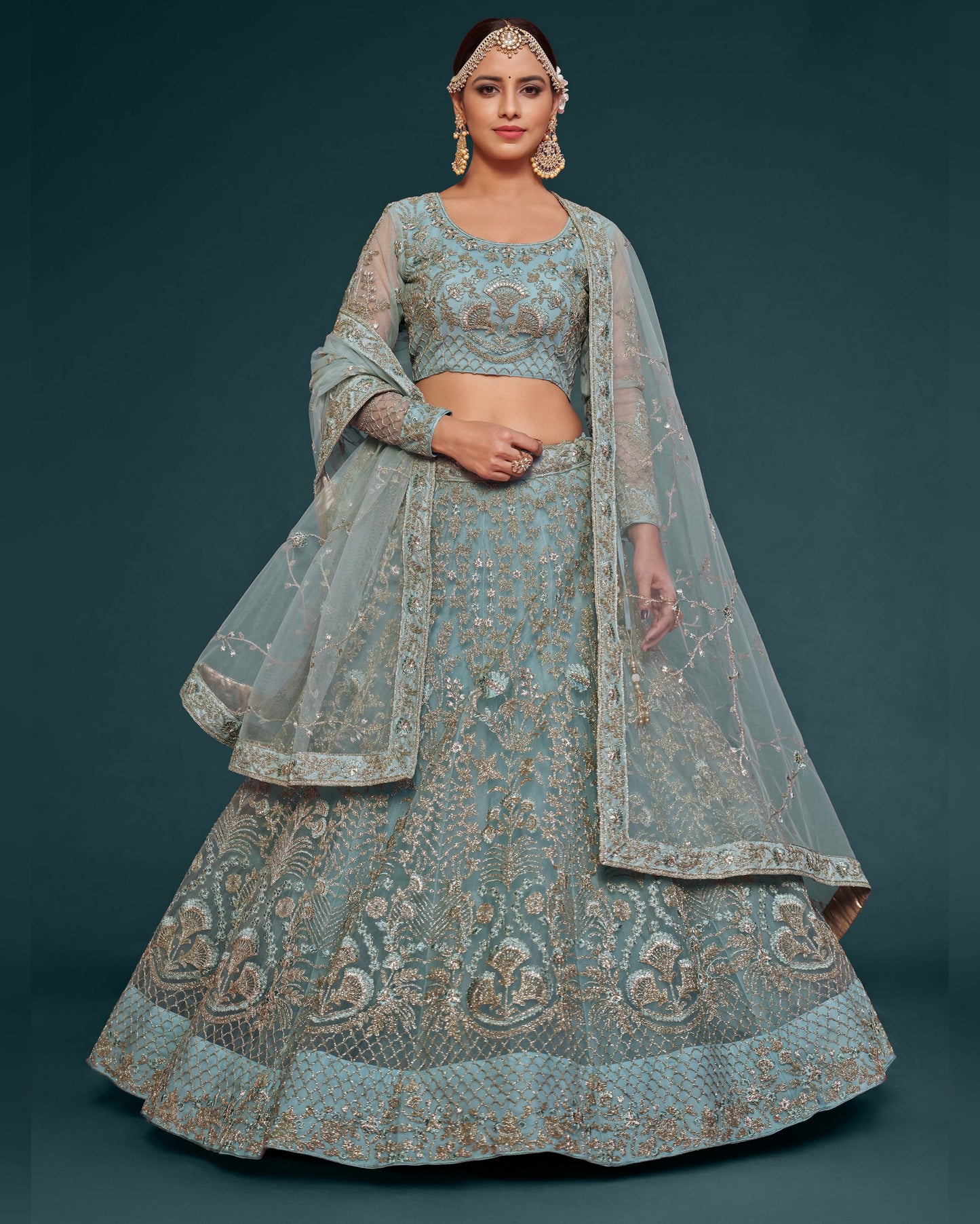 Woman wearing a traditional embroidered lehenga with a matching dupatta on a dark background