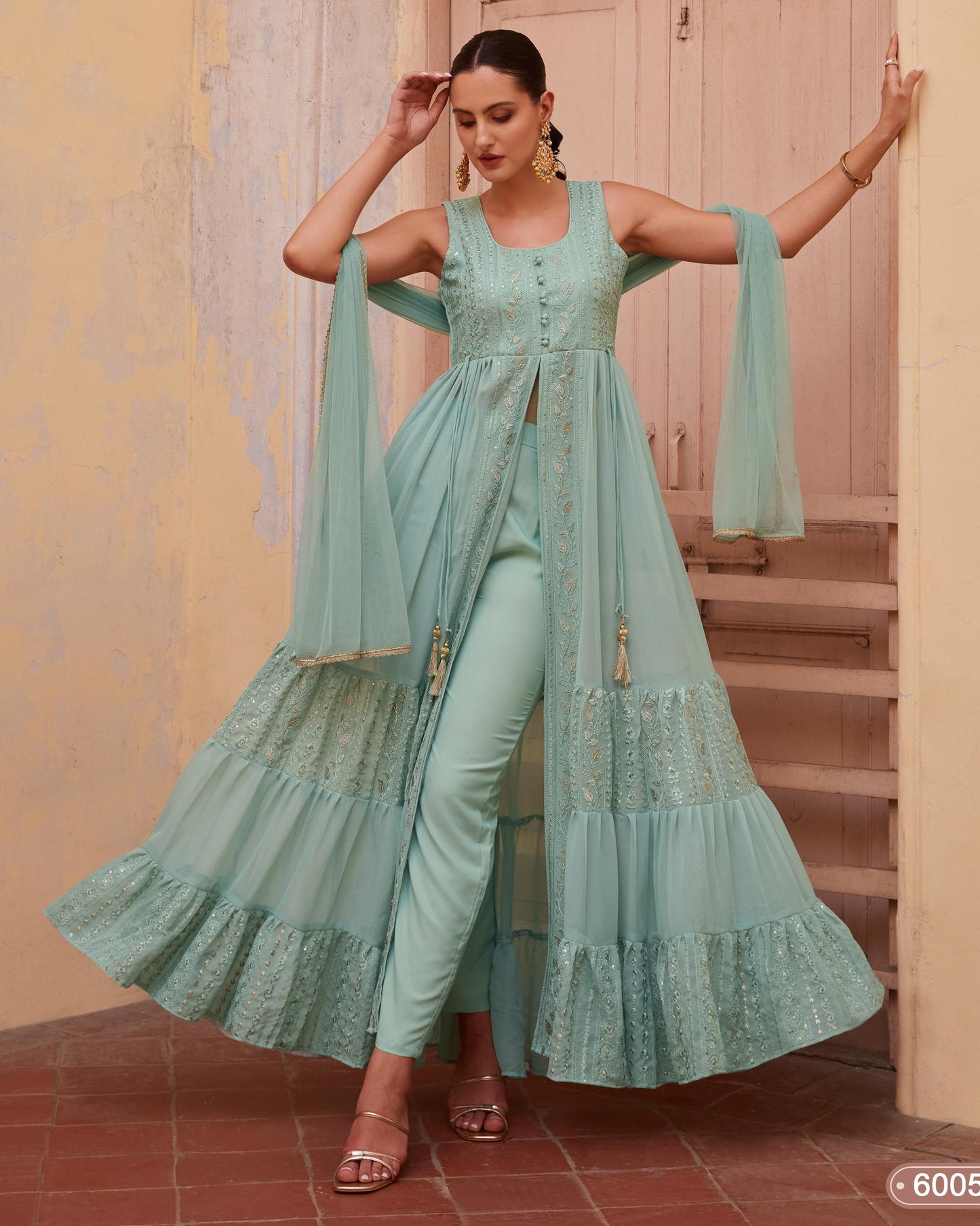 Woman wearing a light blue traditional outfit with a matching dupatta in a warm-toned indoor setting.