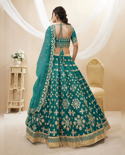Teal embroidered traditional outfit with gold patterns on a neutral background