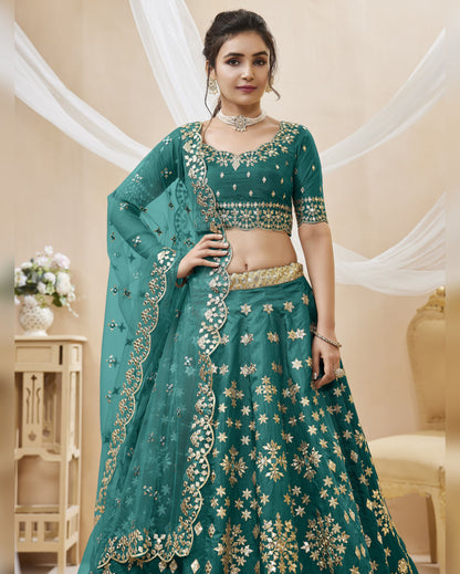 Woman wearing a green embroidered traditional outfit with gold details in an elegant indoor setting.