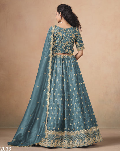 Teal embroidered traditional outfit with gold details on a beige background