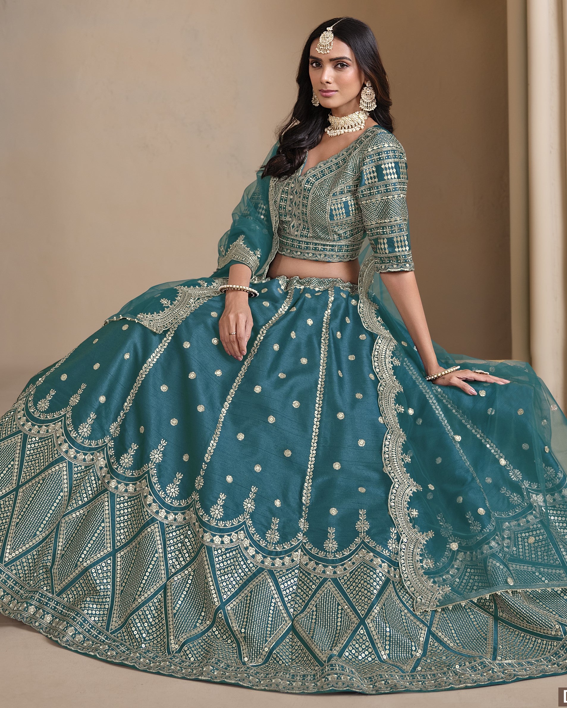 Woman wearing a teal embroidered traditional outfit with a beige background