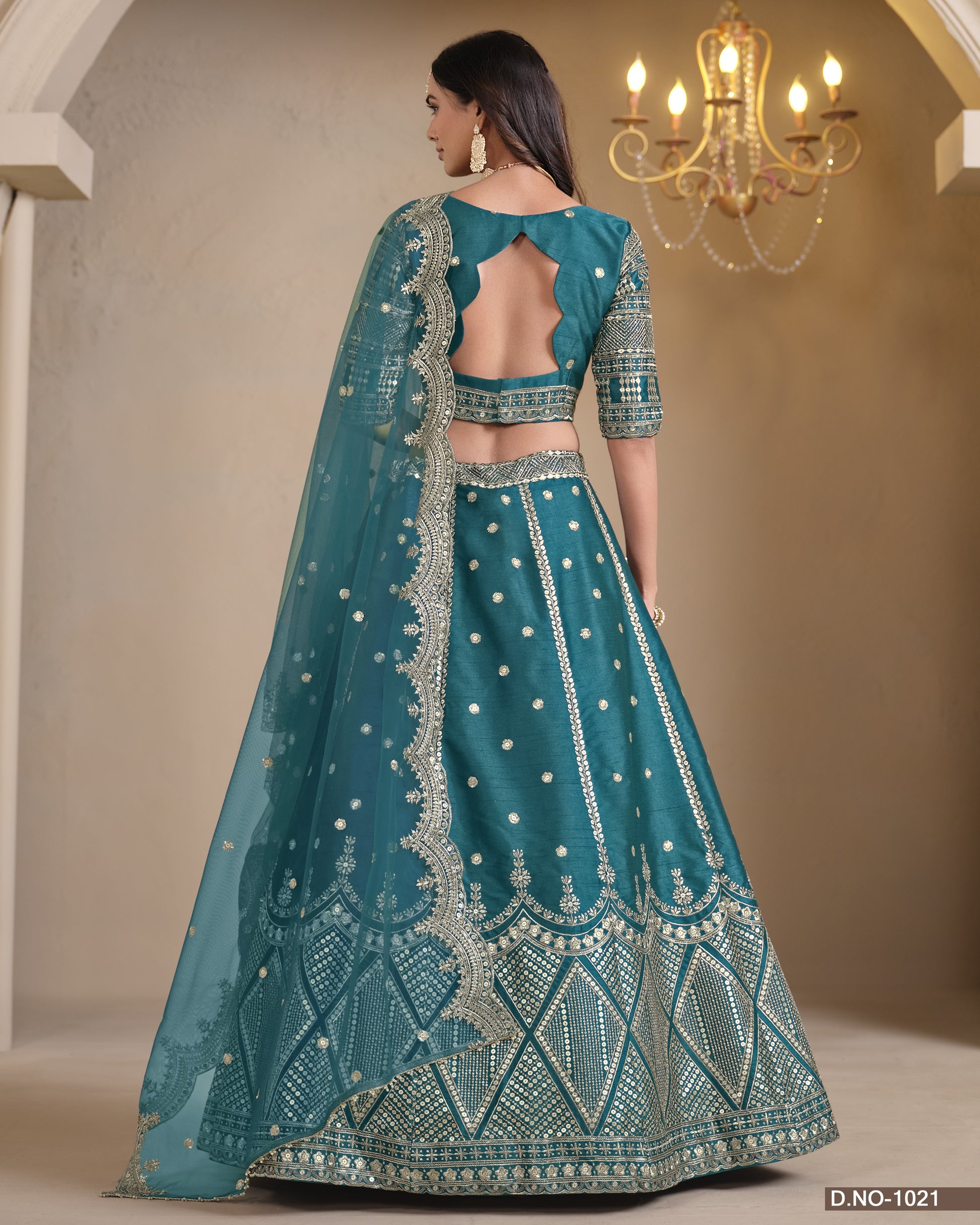 Teal embroidered traditional outfit with a chandelier in the background