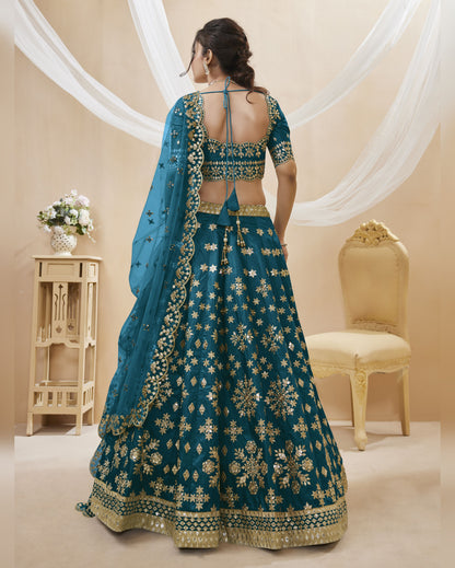 Woman wearing a blue embroidered traditional outfit in a decorated room.