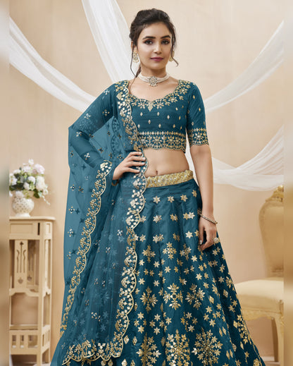 Woman wearing a blue embroidered traditional outfit in an elegant indoor setting.