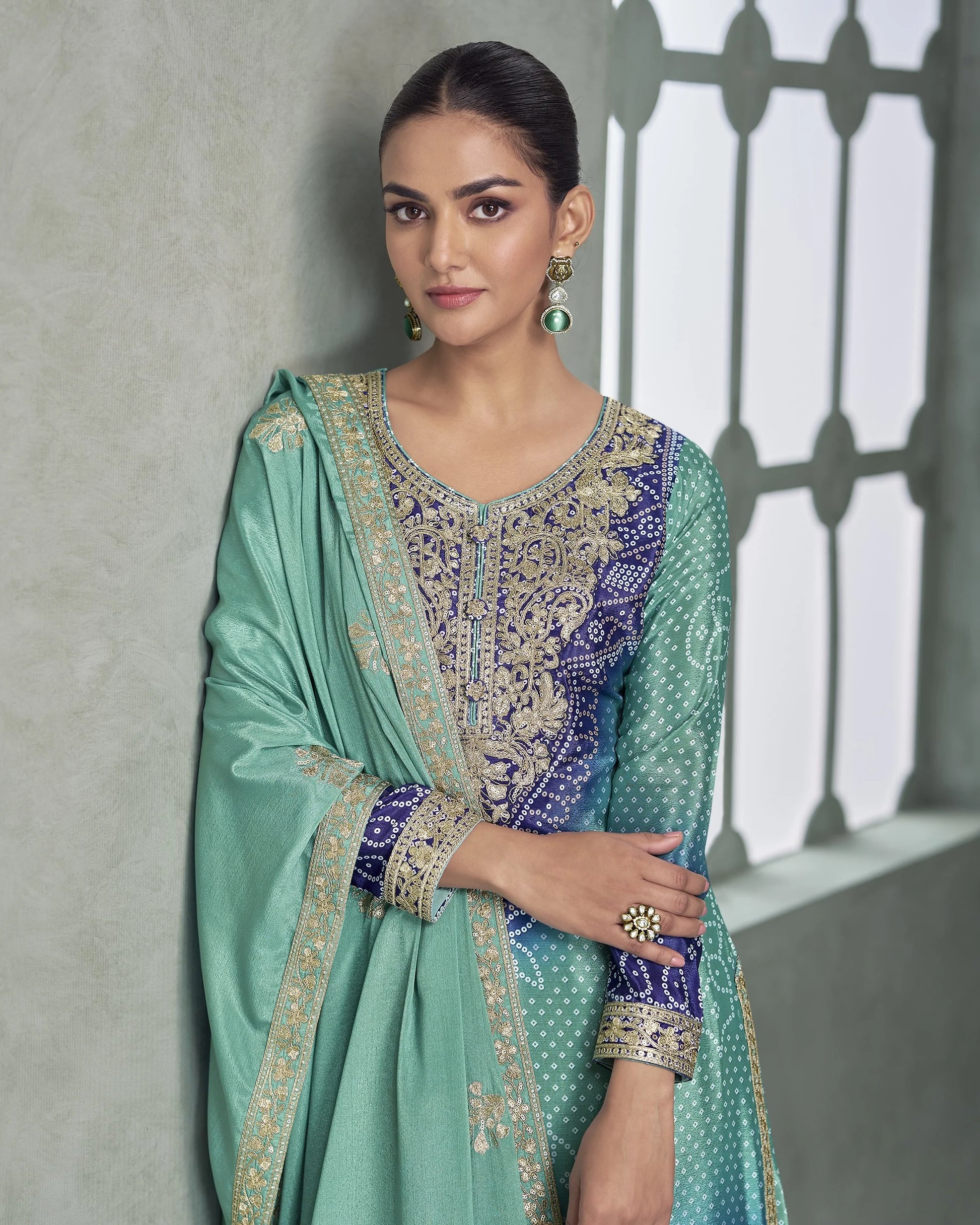 Woman wearing a traditional outfit with intricate patterns against a neutral background