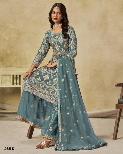 Woman wearing a teal embroidered traditional outfit with a beige background