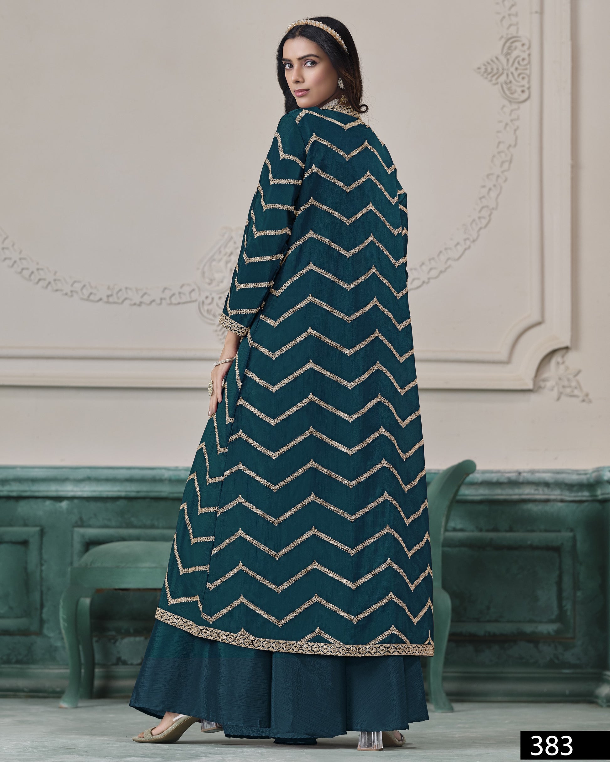 Woman wearing a teal dress with white zigzag pattern in an elegant interior setting.