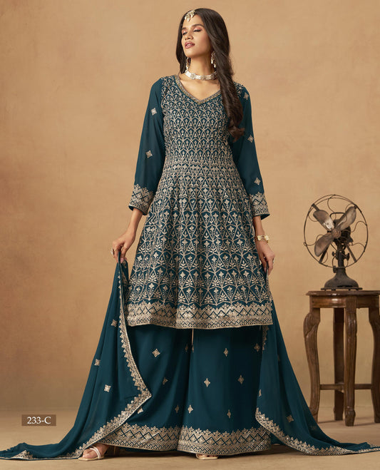Woman wearing a teal and white embroidered traditional outfit with a matching dupatta on a beige background.
