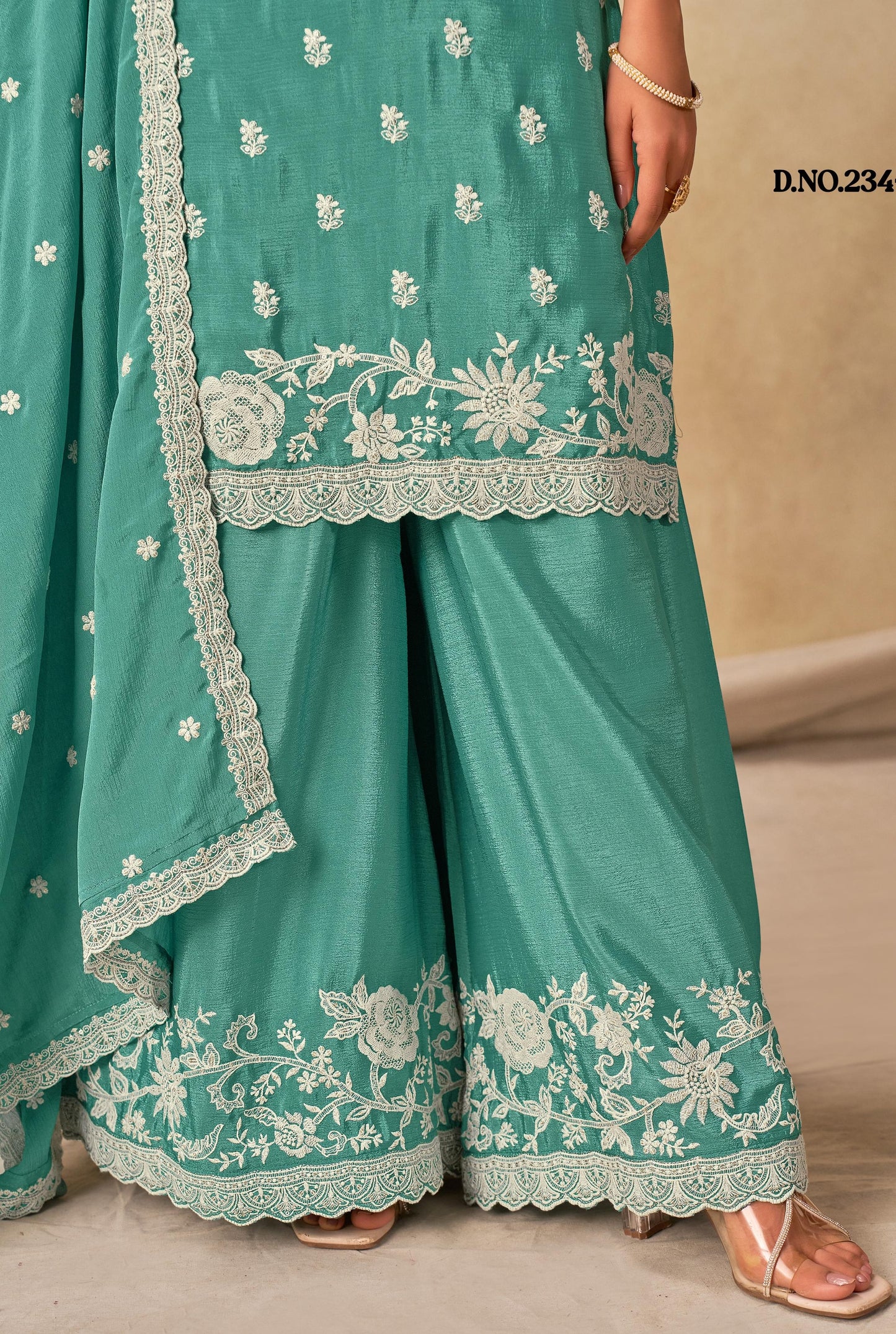 Teal traditional outfit with white floral embroidery on a beige background