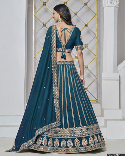 Teal lehenga with intricate embroidery in front of a decorative wall.